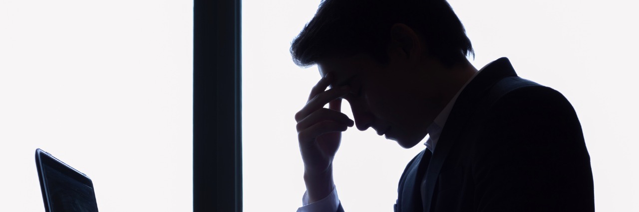 Having Chronic Migraine Should Not Be A Fireable Offense man with headache at office