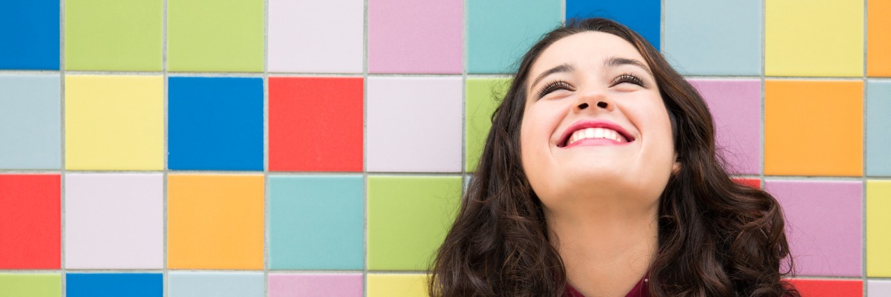 Happy girl laughing against a colorful tiles background.