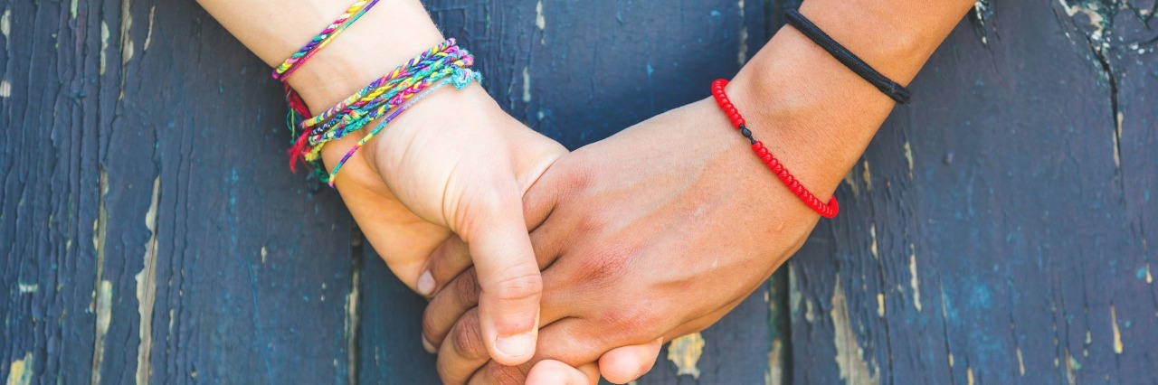 two women holding hands on blue wooden background