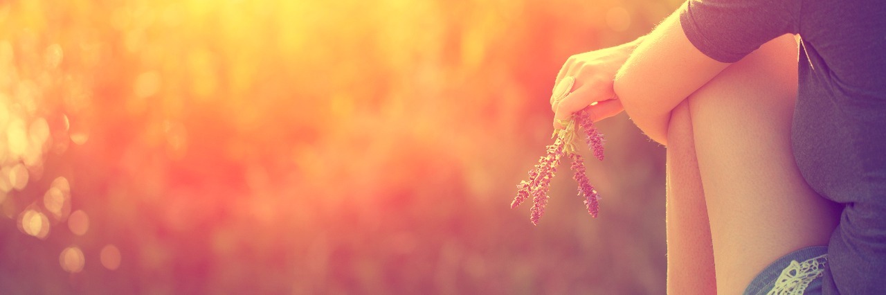 8 Positive Things I've Learned After One Year With Ulcerative Colitis girl sitting in grass with sun shining