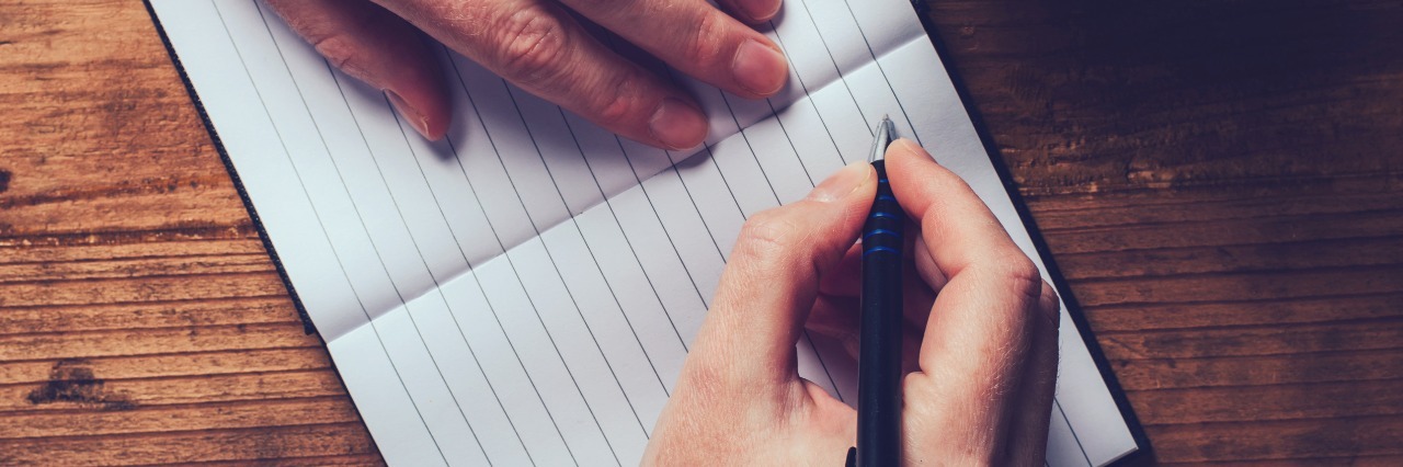 How to Find the Good in Each Day With Depression woman drinking coffee and writing in diary - top view, on a wooden table