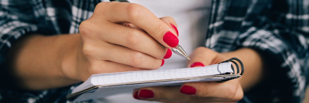 A Letter to My Former Self, Before I Became Ill Woman in plaid shirt and a red manicure pen writing in a notebook