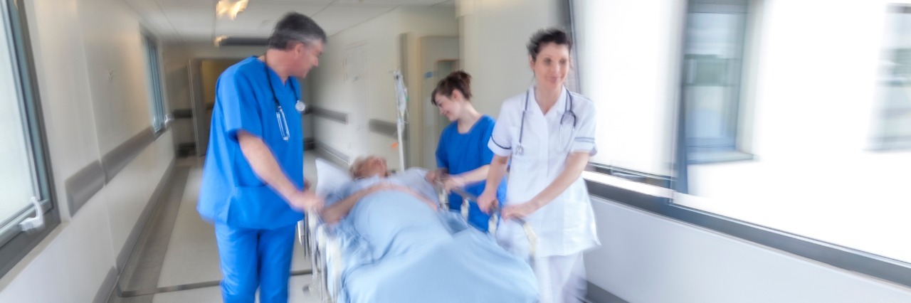 emergency room staff wheeling a patient down a hallway on a gurney