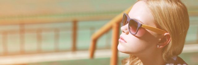 Woman outside wearing sunglasses, wit a thoughtful expression.
