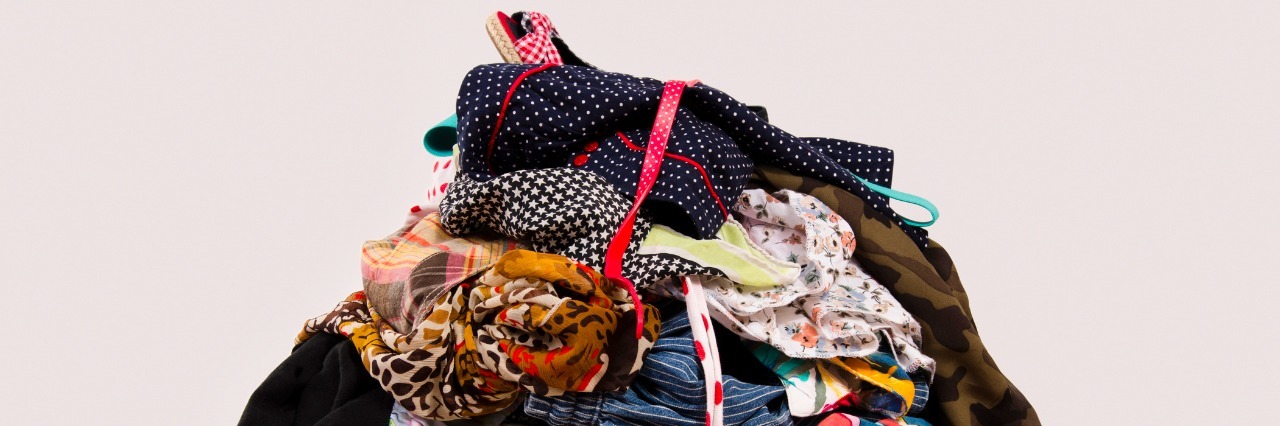 Untidy cluttered wardrobe with colorful clothes and accessories on the ground.