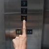 Woman's hand pressing number "one" on an elevator.