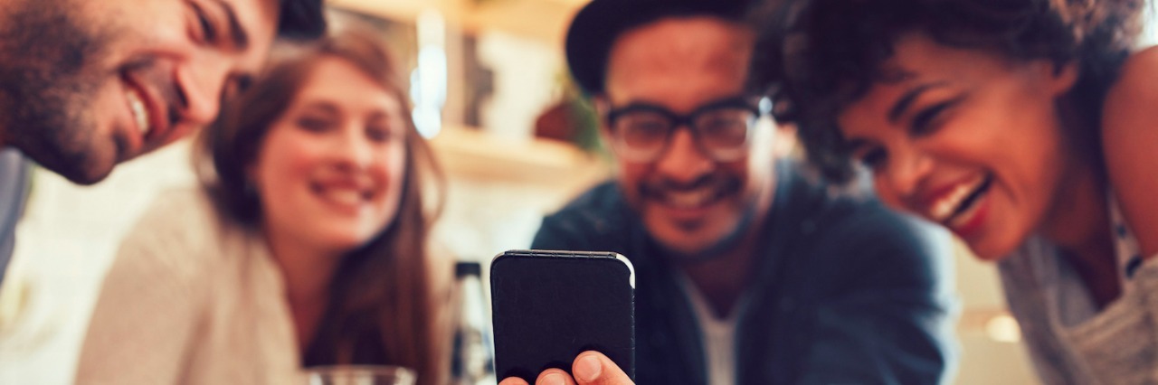 5 Autism Stereotypes I Fit, and 5 I Don't Group of friends at table, looking at smart phone