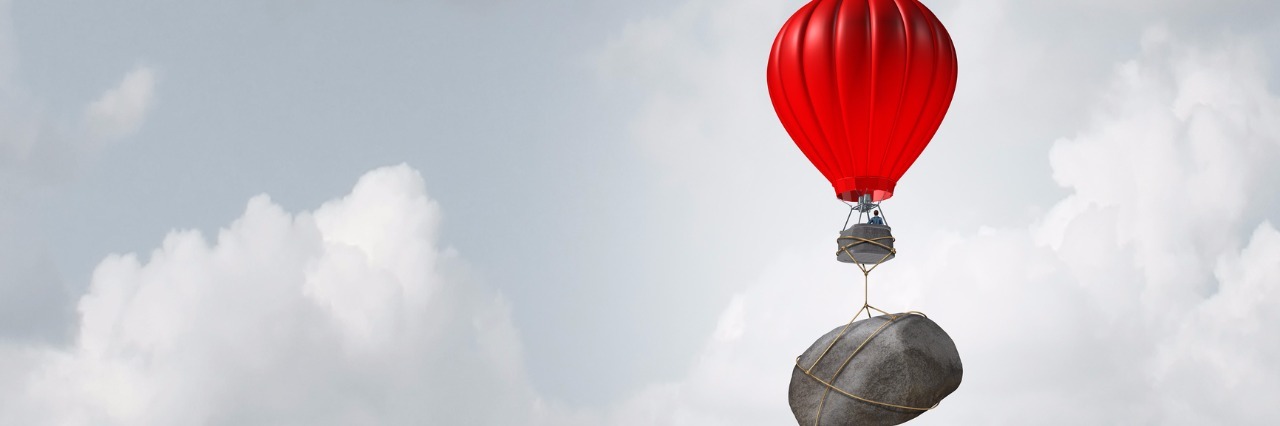 When My Lupus Is Being a 'Jerk' Hot air balloons floating in sky, one being held back due to rock weighing it down.