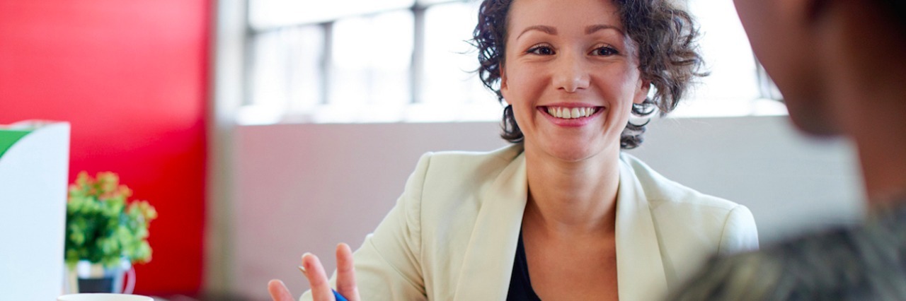 When I Hear ‘Grow a Thicker Skin’ as Someone With Scleroderma Photo of two women in a business meeting, one woman holding a tablet