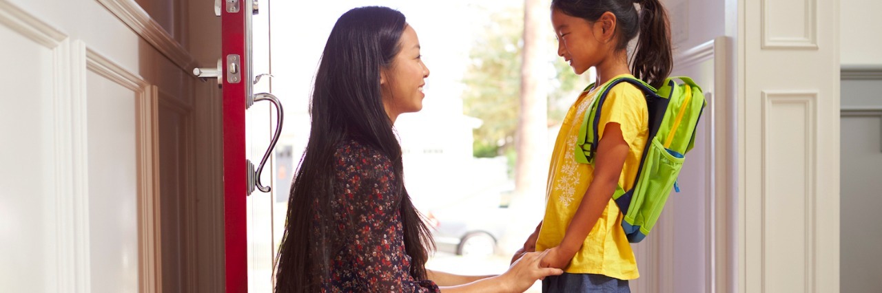 Letter to the Single Parent With a Child on the Spectrum Mother and daughter in front of open door at home, with daughter wearing backpack, and mom holding daughter's hands