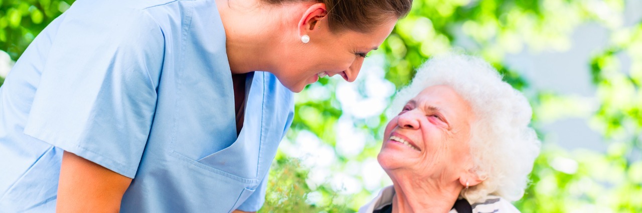 Nurse holding hand of senior woman in pension home