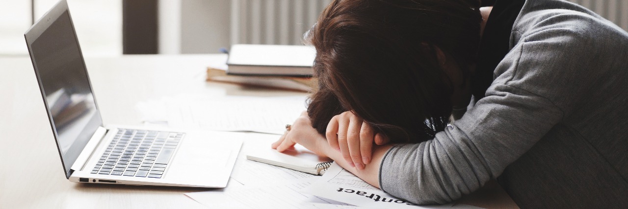 The Importance of Avoiding Post-Exertional Malaise With ME/CFS woman with her head down asleep at her desk