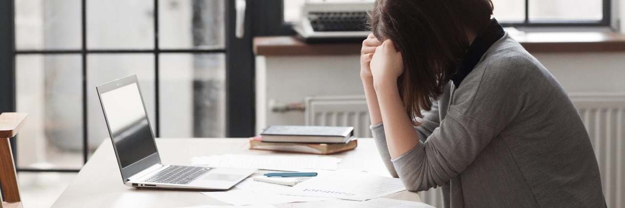 Revealing My Bipolar Disorder to My Co-Workers stressed business woman at office with head in hands
