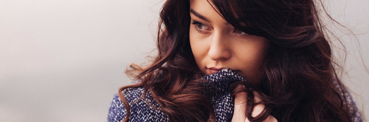 Why Someone With Chronic Illness Says 'I'm Fine' woman wrapping her blue coat around herself