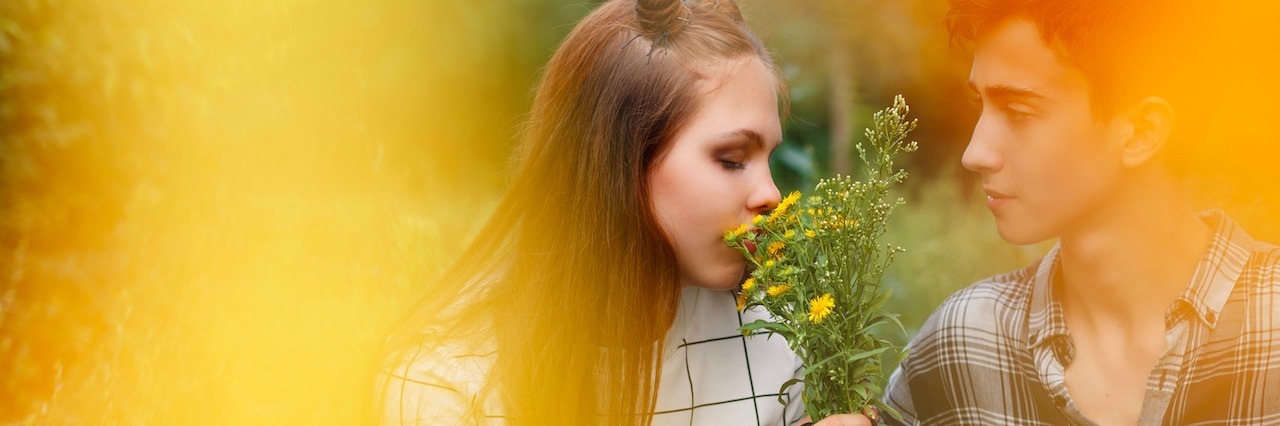12 Things to Remember When You Love Someone With Anxiety couple sitting together outside. The girl smells flowers