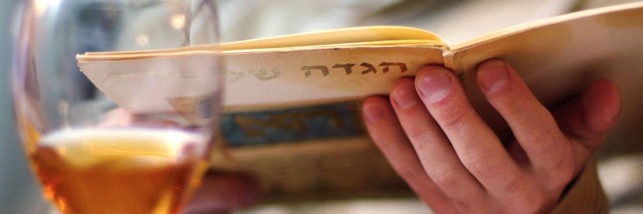 Why This Passover Will Be Different for My Eating Disorder Recovery man reading haggadah book during passover seder dinner