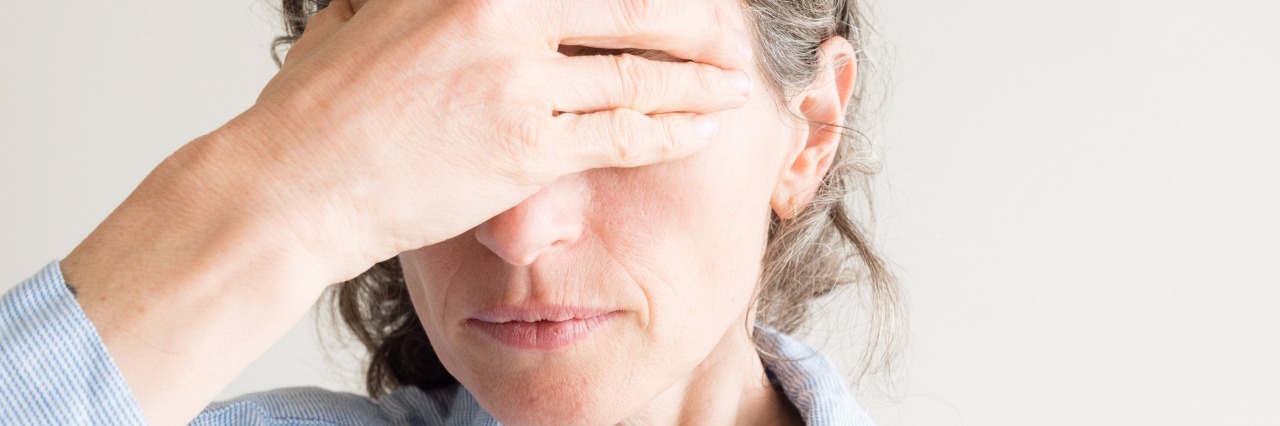 Many Feelings of Grief After Asthma Diagnosis woman covering her eyes with her hand in grief