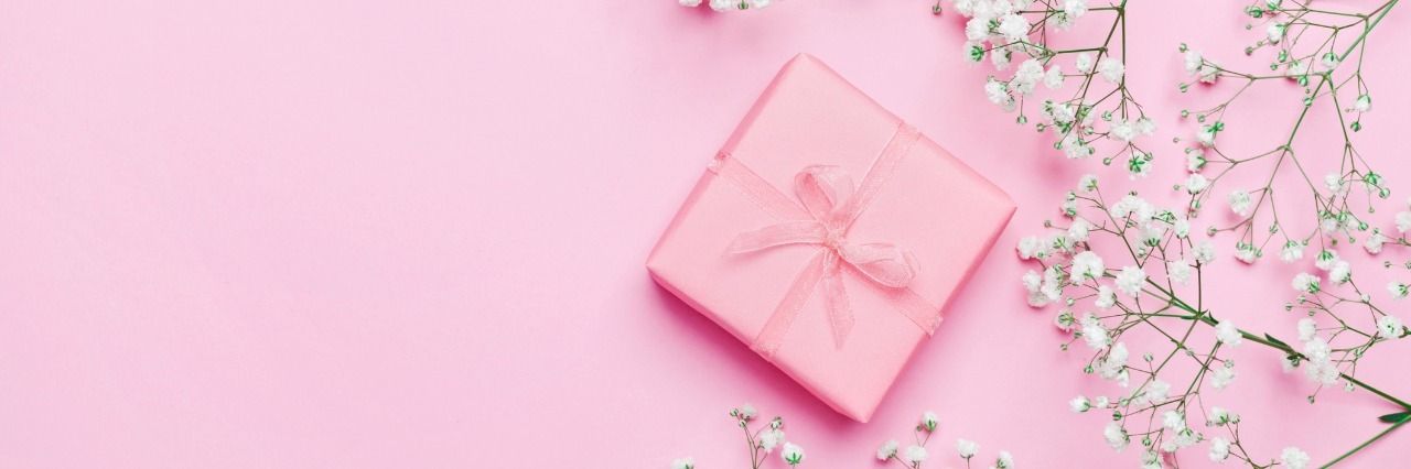 Positive Things About Having a Chronic Illness Gift or present box and flower on pink table from above. Pastel color.