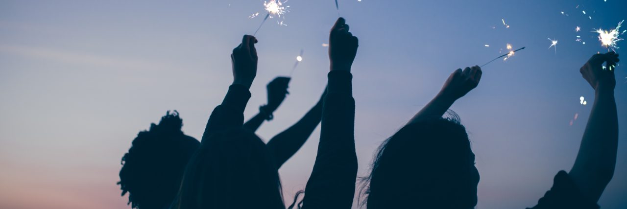 Making Friends While Struggling With Mental Illness Friends celebrate new year's eve party with sparklers and firework at sunset