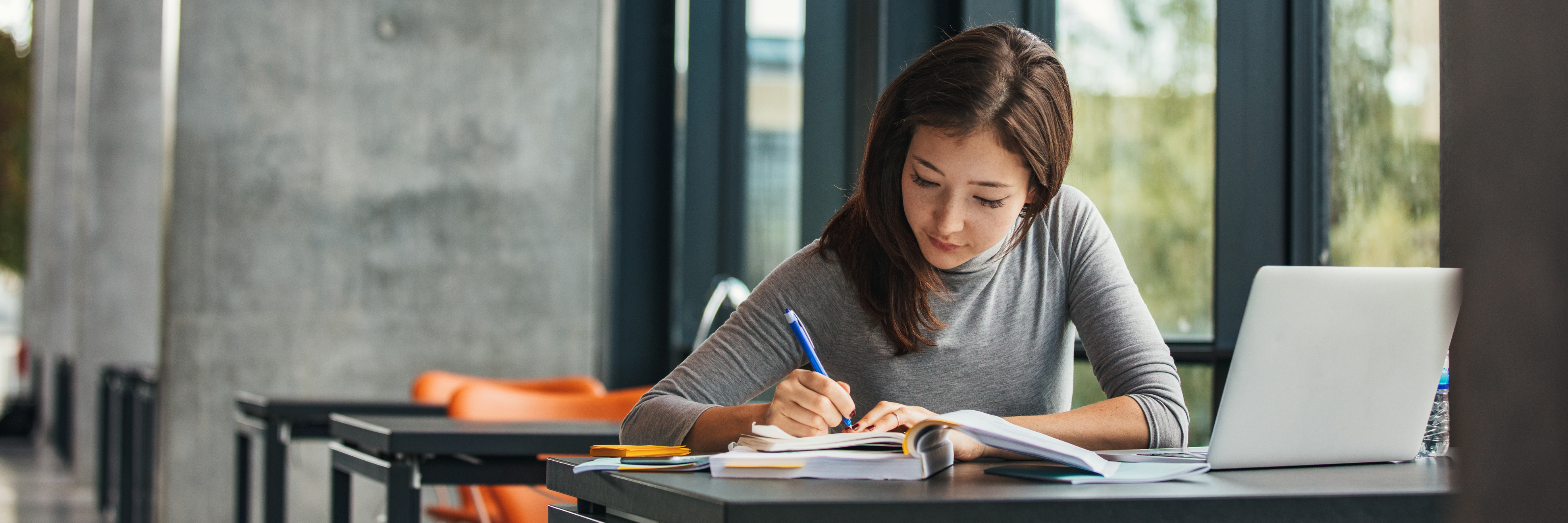 Shot of young asian female student sitting at table and writing on notebook. Young female student studying in library.