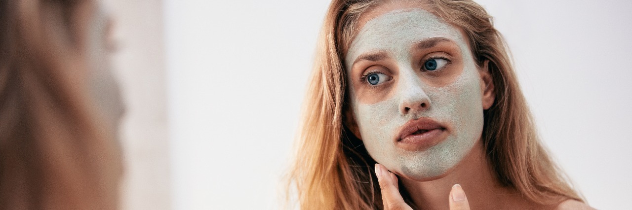 The Mask I Wear to Hide My Depression blonde woman looking into mirror applying face mask