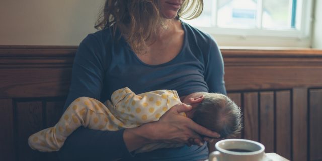 Woman breastfeeding baby in cafe