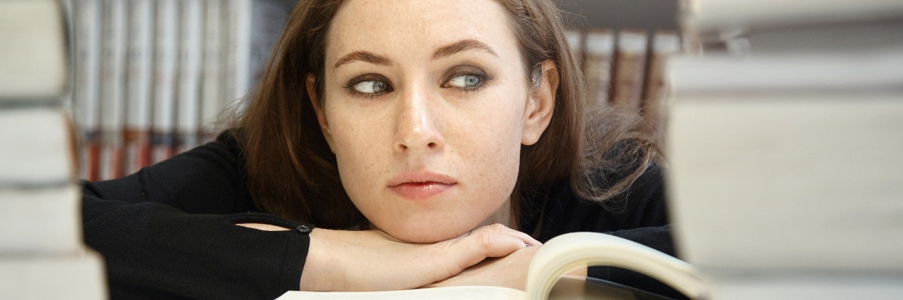 What It's Like to Function Through a Depressive Episode female college student surrounded by books looking tired