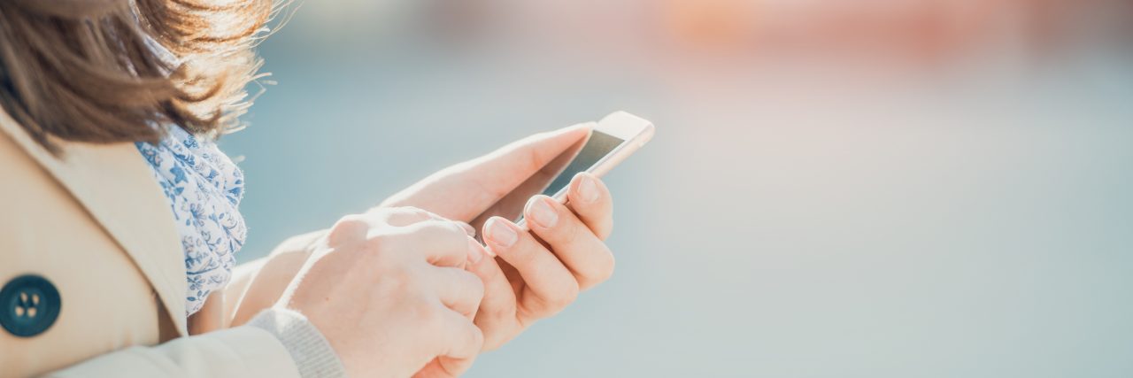 What to Text a Friend Experiencing Anxiety Young woman walking and using a smart phone on a city street.