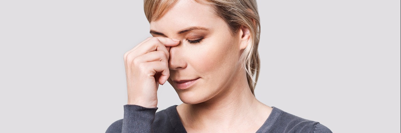 What Not to Say to Someone With Chronic Pain, Migraines woman pinching the bridge of her nose in frustration