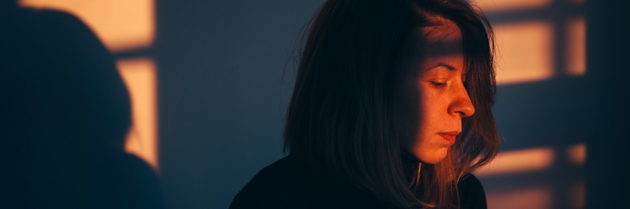 Why I'm Not 'Too Young to Feel Tired' With Fibromyalgia, Depression A woman sitting alone and sad in window light