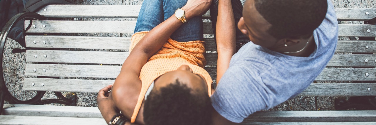 What It Means to Fall in Love With Someone Who's Chronically Ill couple sitting on a bench holding hands