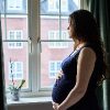Pregnant woman in front of window in UK.