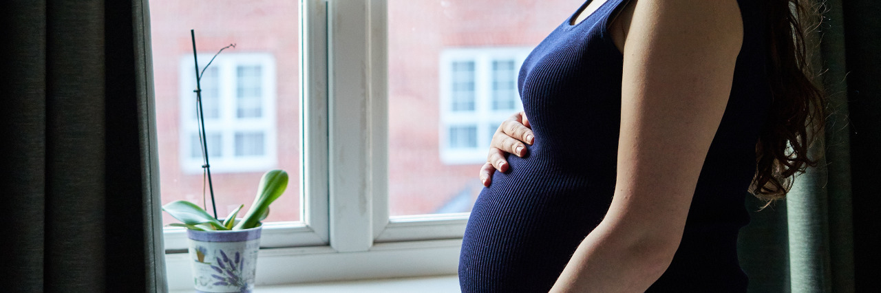 Pregnant woman in front of window in UK.