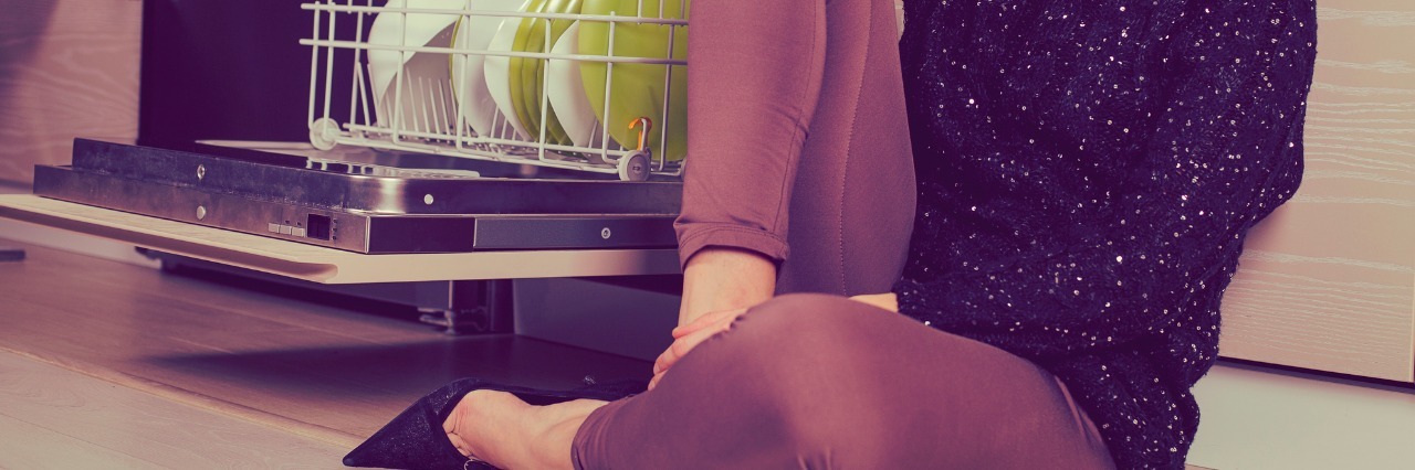 Why I Laughed When I Passed Out From Dysautonomia woman sitting on kitchen floor next to dishwasher