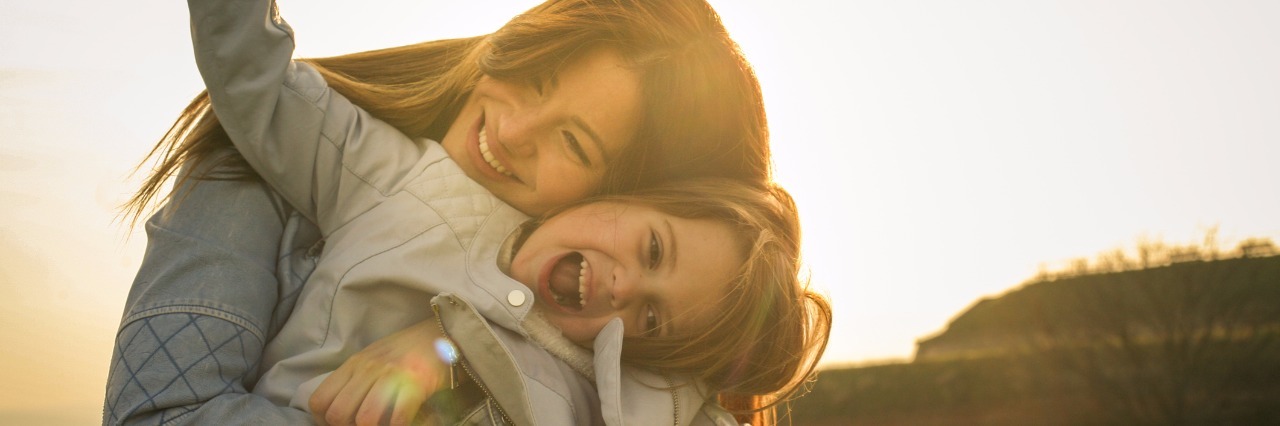 Feeling Guilty as a Mother With Migraines mother hugging her daughter outdoors