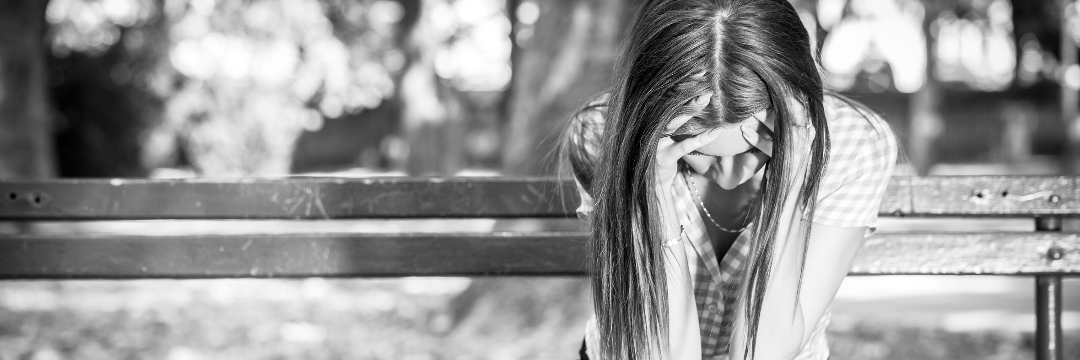 Why I Don't Want to Avoid My Biggest Trigger sad young woman sitting on bench in park