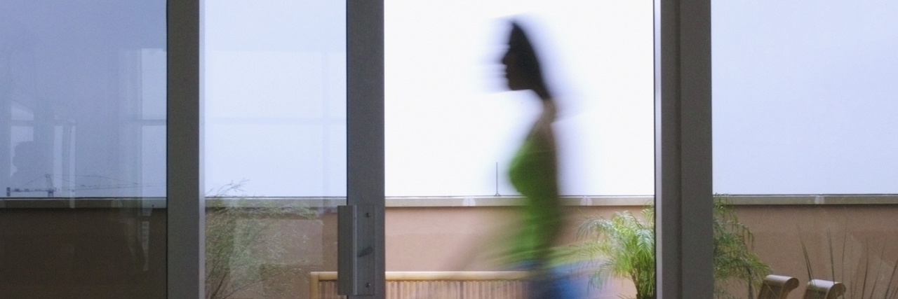 A woman walking past a glass sliding door