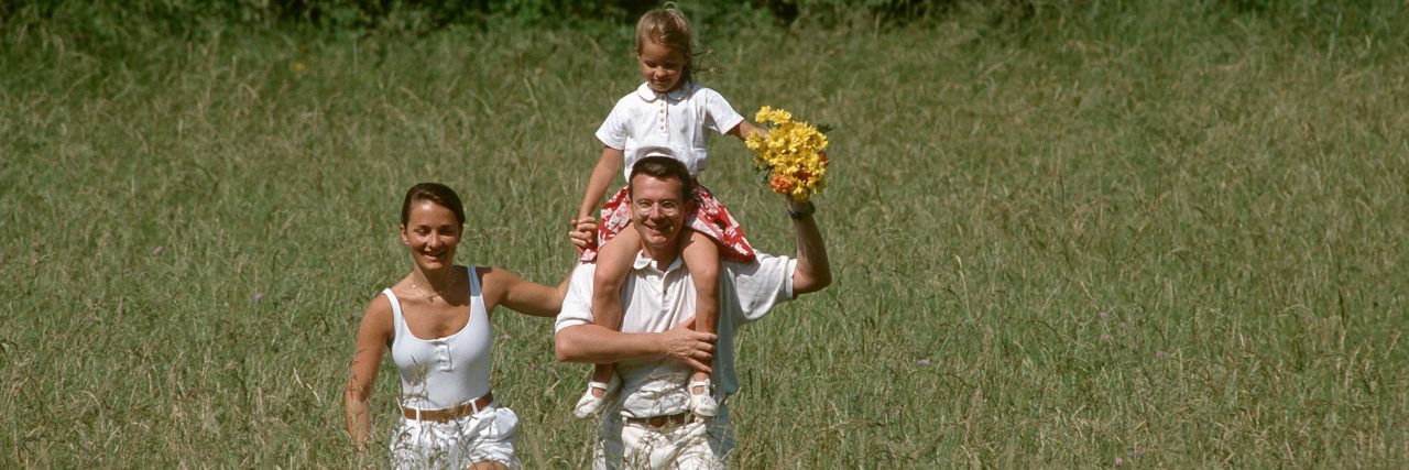 Family walking in a field on a sunny day.