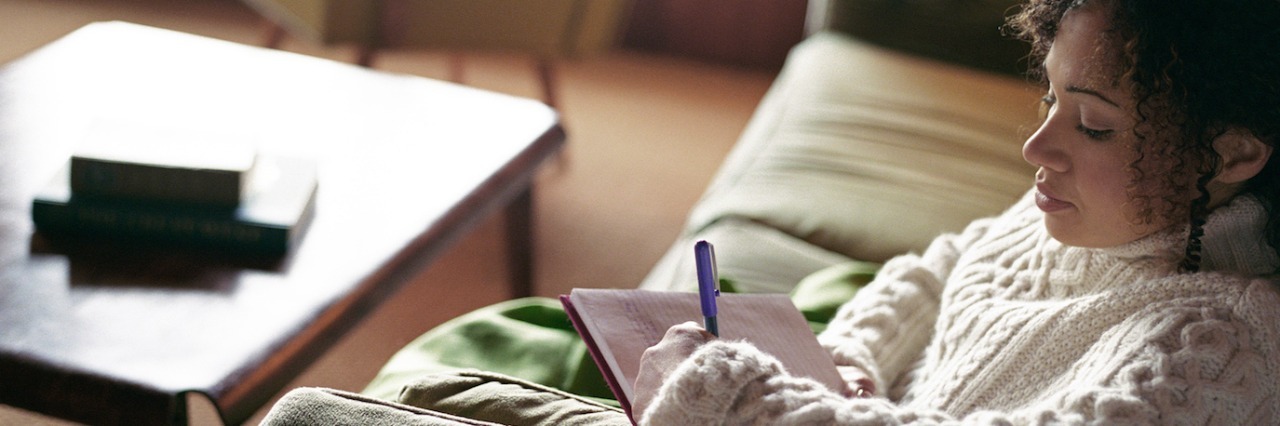 Woman sitting on sofa, writing letter