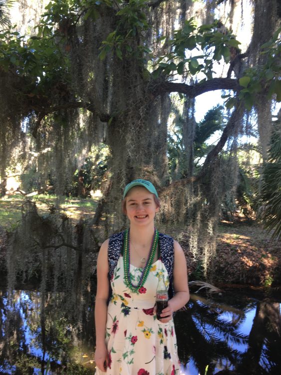 girl standing under large tree