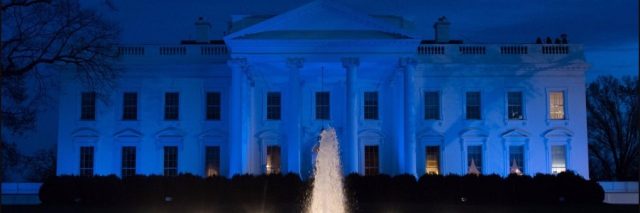 Photo of the White House lit blue.