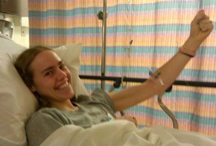 young woman smiling in hospital bed with tubes attached to her arm