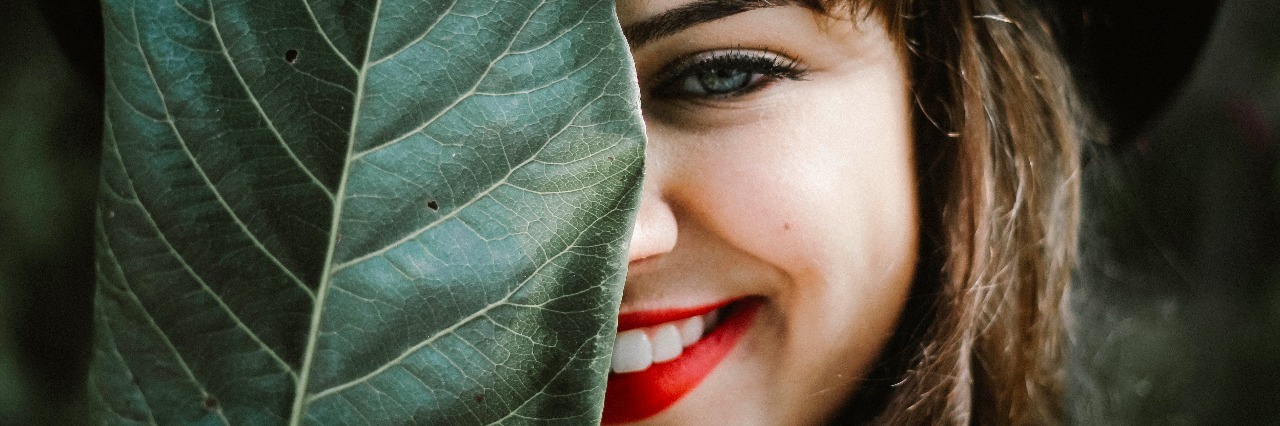 How Smiling Helps Me Hide My Anxiety From Others girl hiding leaf