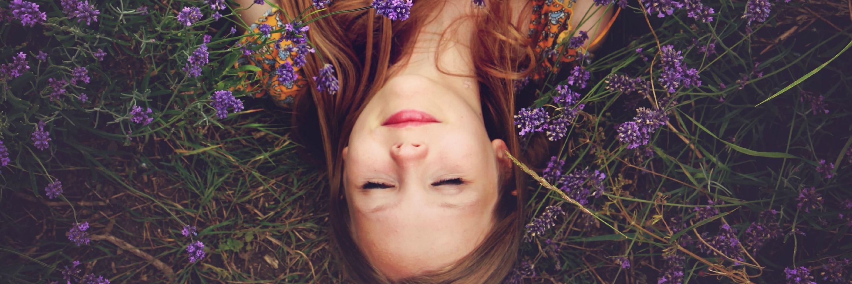 woman at peace lying on her back in purple flowers