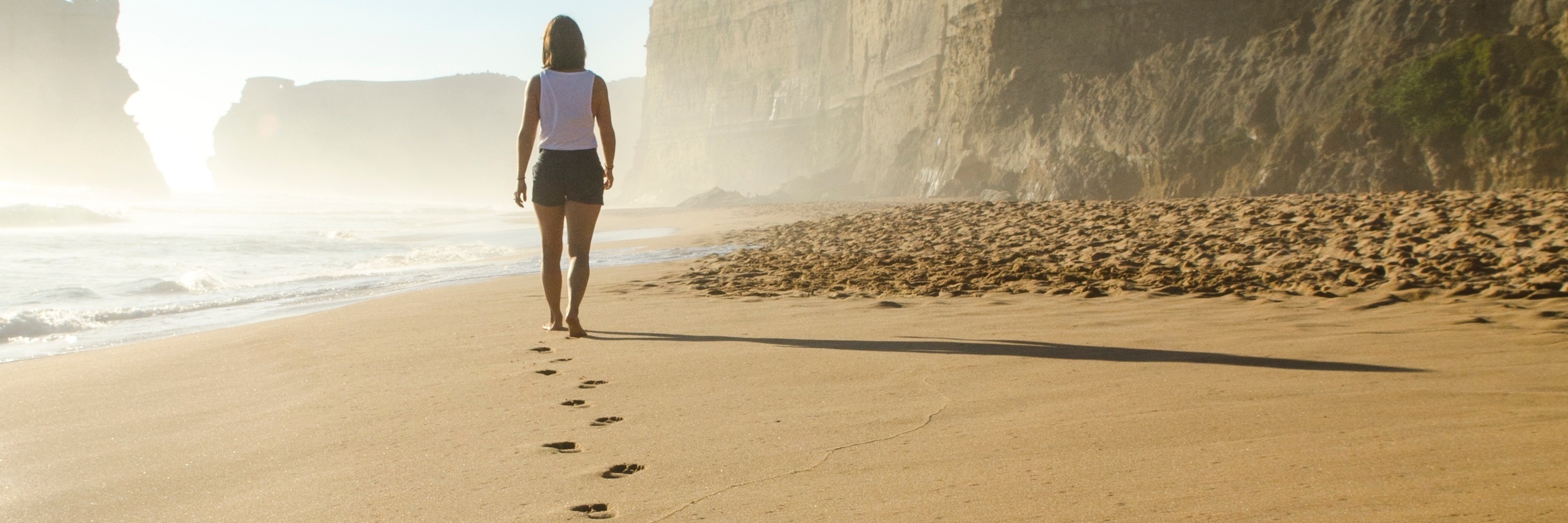 How I Discovered the Importance of Seeking Treatment With Anxiety beach footprints in sand leading to woman in distance