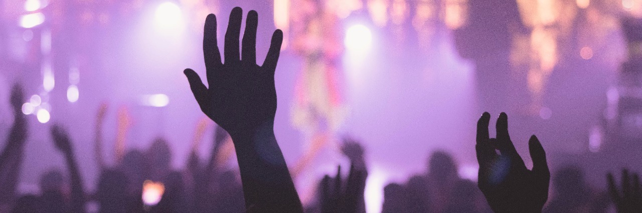 nightlife crowd hands raised in club with purple lights