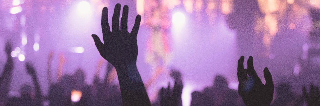 Why My Anxiety Means I Take a Week to Get Ready for a Night Out nightlife crowd hands raised in club with purple lights