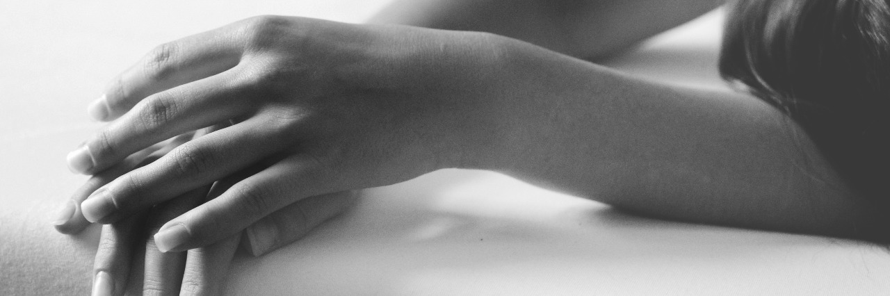 Unable to Get Out of Bed Because of Depression close up of woman's hands and arms in bed black and white