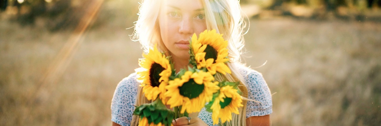 woman with blonde hair holding sunflowers