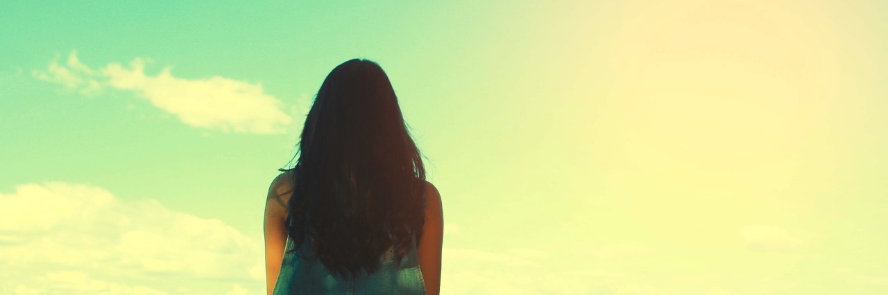 Why I Take Nothing for Granted After My Cancer Diagnosis A woman sitting by the edge of the water looking at the sky